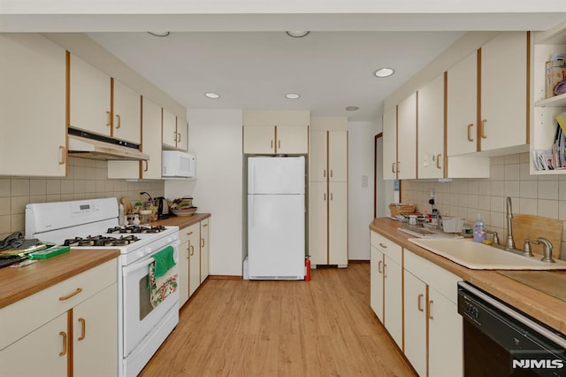 kitchen with white appliances, a sink, white cabinets, under cabinet range hood, and light wood-type flooring