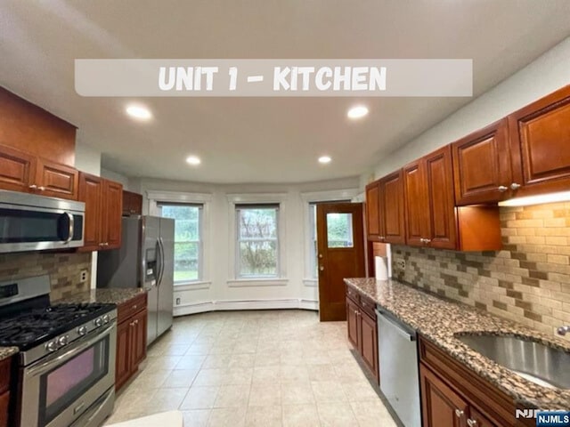 kitchen featuring backsplash, appliances with stainless steel finishes, sink, and dark stone countertops