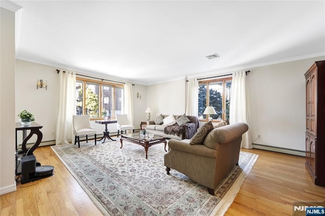 living room with light hardwood / wood-style flooring, a baseboard radiator, ornamental molding, and plenty of natural light