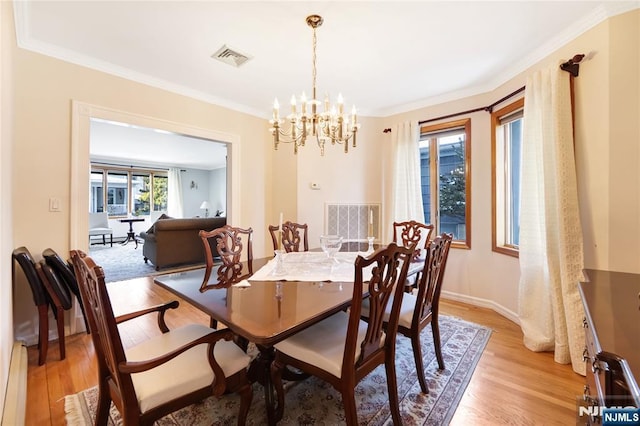 dining space featuring ornamental molding, a notable chandelier, and light hardwood / wood-style flooring