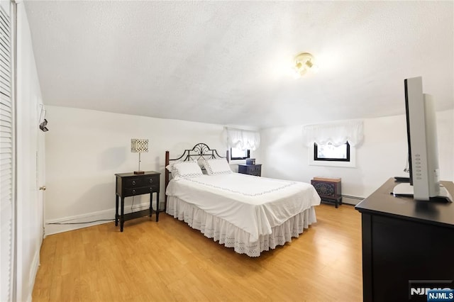 bedroom featuring hardwood / wood-style flooring, a baseboard radiator, and a textured ceiling