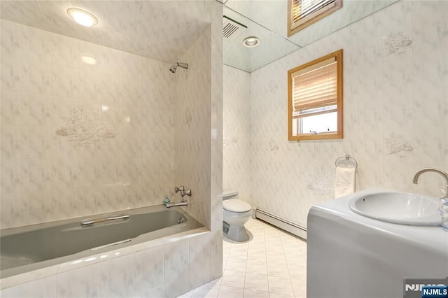 full bathroom featuring sink, tile walls, tiled shower / bath combo, baseboard heating, and toilet