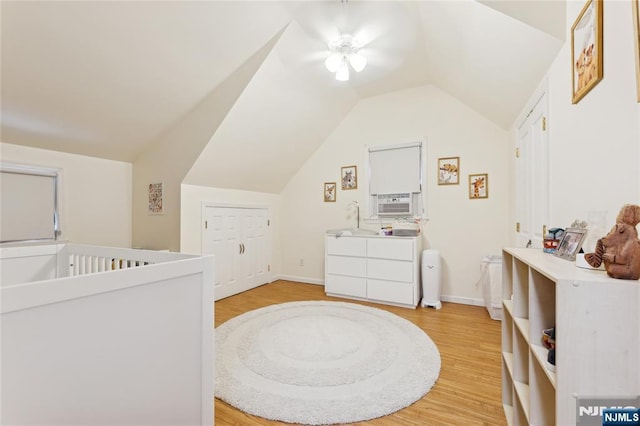 bedroom featuring ceiling fan, light wood-type flooring, vaulted ceiling, and cooling unit