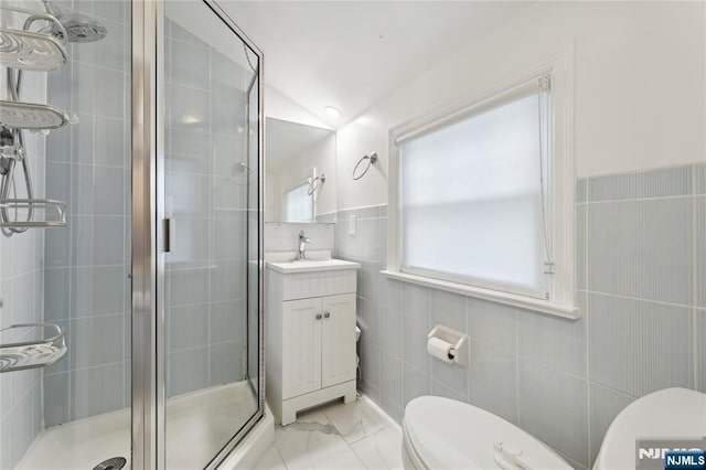 bathroom featuring a shower with door, lofted ceiling, toilet, tile walls, and vanity