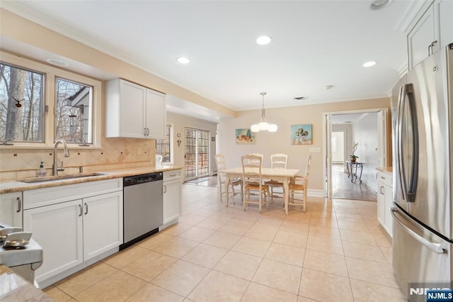 kitchen featuring crown molding, pendant lighting, decorative backsplash, stainless steel appliances, and a sink