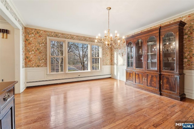 unfurnished dining area featuring baseboard heating, a chandelier, and wainscoting