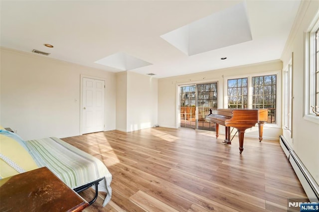 sitting room with light wood-type flooring, visible vents, ornamental molding, a baseboard heating unit, and baseboards