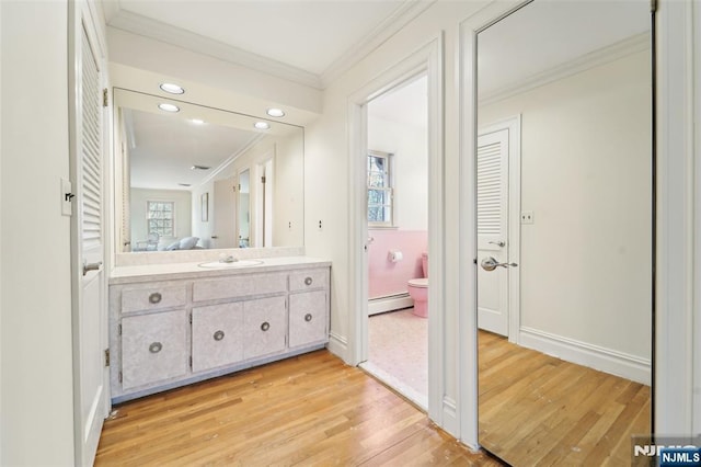 bathroom featuring a baseboard heating unit, toilet, wood finished floors, and ornamental molding