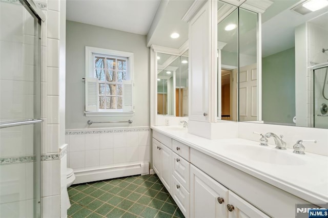 full bath with a sink, a shower stall, toilet, tile walls, and a baseboard radiator