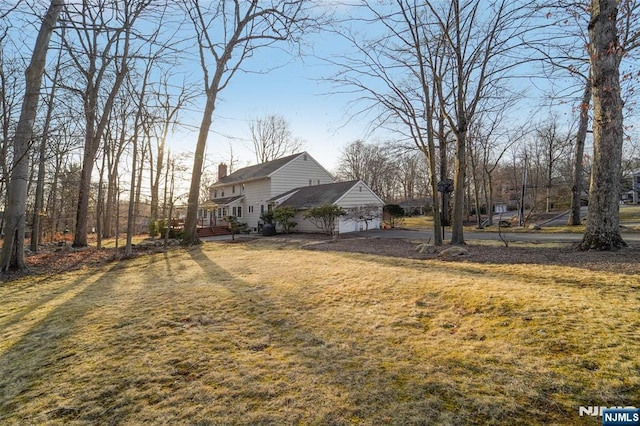 view of side of home with a lawn, a deck, and a chimney