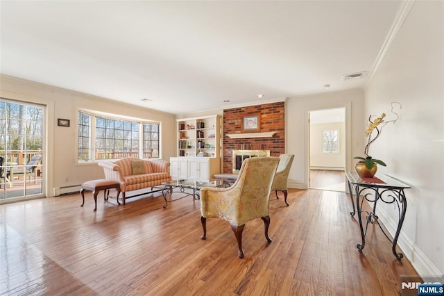 living room featuring visible vents, ornamental molding, a fireplace, light wood finished floors, and a baseboard radiator