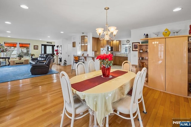 dining space featuring recessed lighting, light wood finished floors, and an inviting chandelier