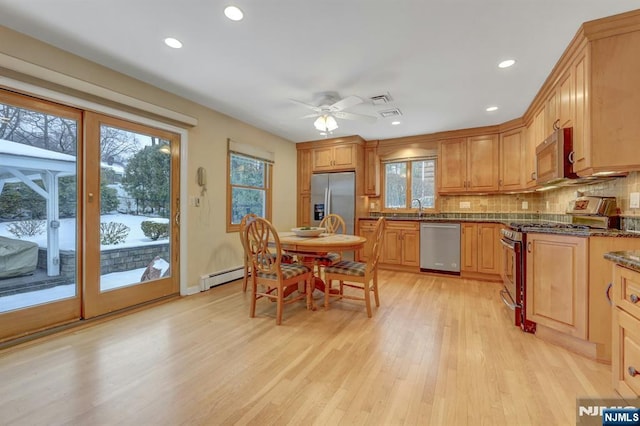 kitchen with stainless steel appliances, a baseboard heating unit, a sink, and tasteful backsplash