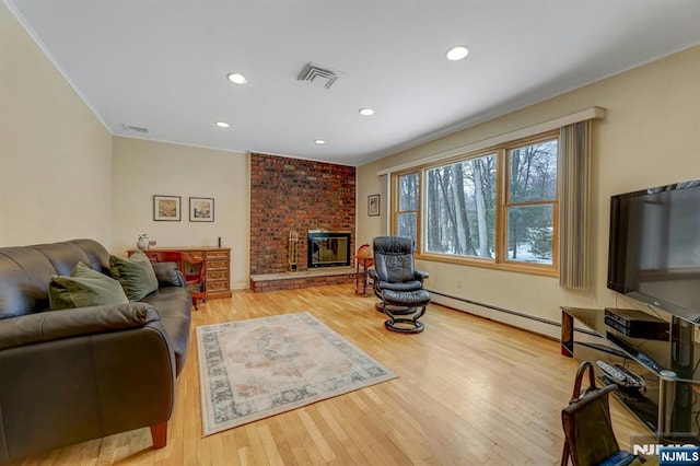 living room with visible vents, a fireplace, and light wood-style flooring