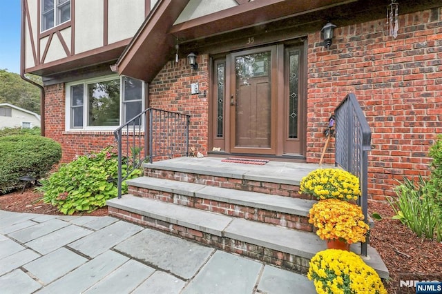 view of exterior entry featuring brick siding and stucco siding