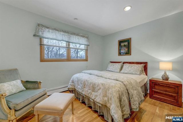 bedroom with light wood finished floors, baseboard heating, and recessed lighting