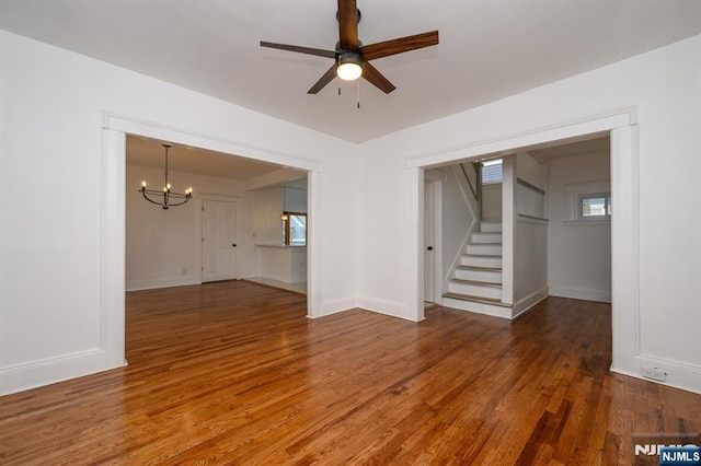 interior space with ceiling fan with notable chandelier and dark hardwood / wood-style flooring