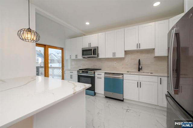 kitchen with sink, appliances with stainless steel finishes, hanging light fixtures, light stone countertops, and white cabinets