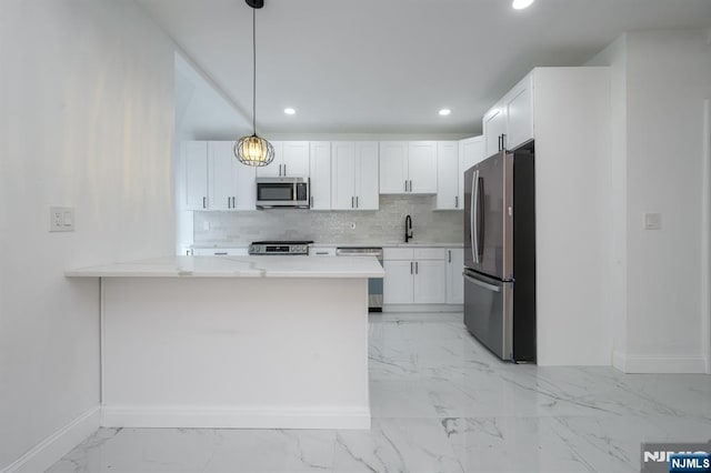 kitchen with appliances with stainless steel finishes, pendant lighting, white cabinetry, backsplash, and kitchen peninsula