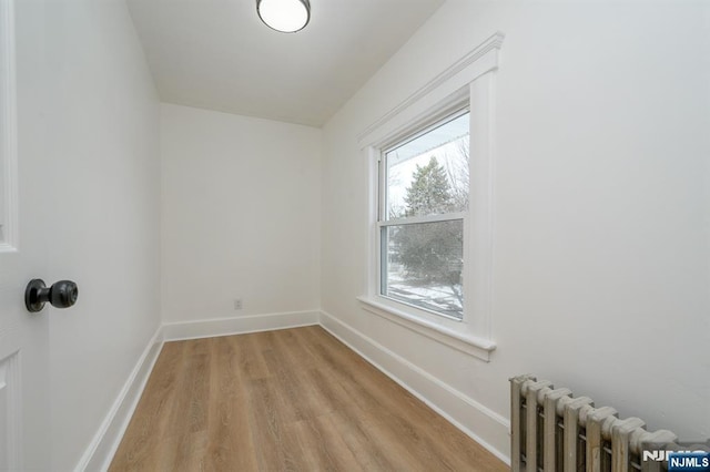 unfurnished room featuring radiator and light wood-type flooring