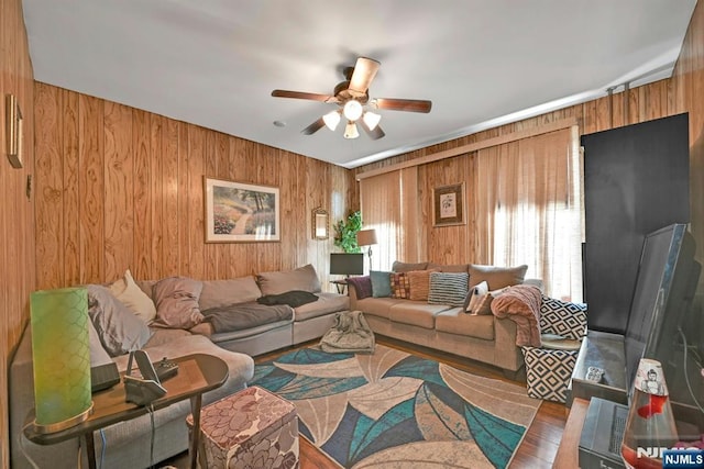 living room with ceiling fan, hardwood / wood-style floors, and wood walls