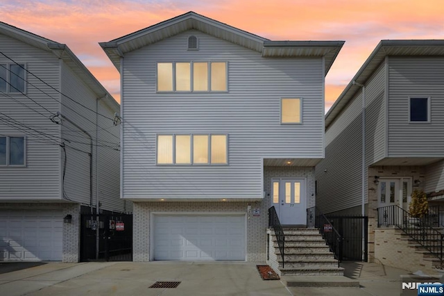 view of front of house featuring a garage, concrete driveway, brick siding, and entry steps