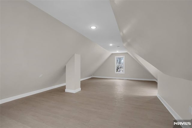 bonus room featuring vaulted ceiling and light wood-type flooring