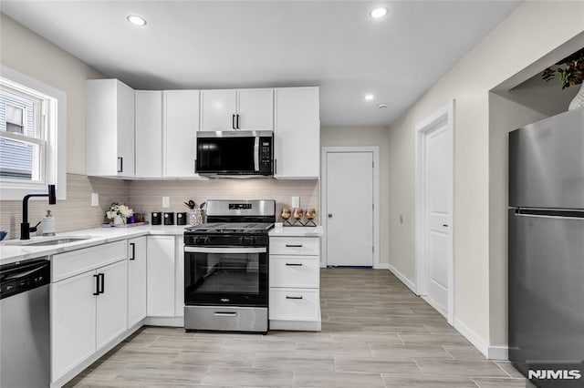 kitchen with white cabinetry, appliances with stainless steel finishes, sink, and tasteful backsplash