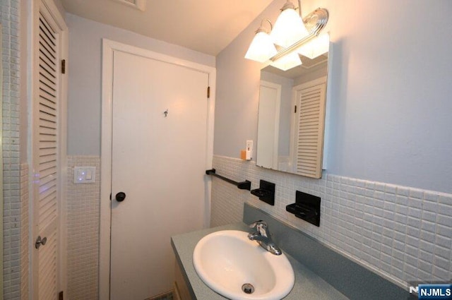 bathroom featuring wainscoting, vanity, and tile walls