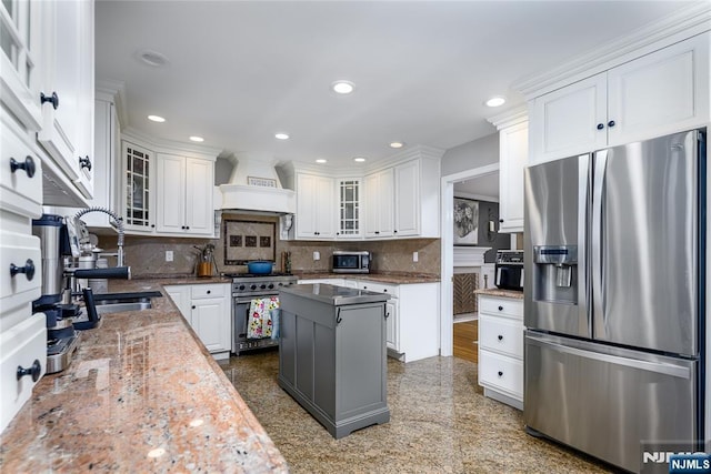 kitchen with a center island, custom exhaust hood, stainless steel appliances, glass insert cabinets, and white cabinets