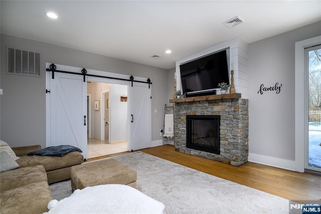 living area featuring light wood finished floors, a barn door, visible vents, and recessed lighting