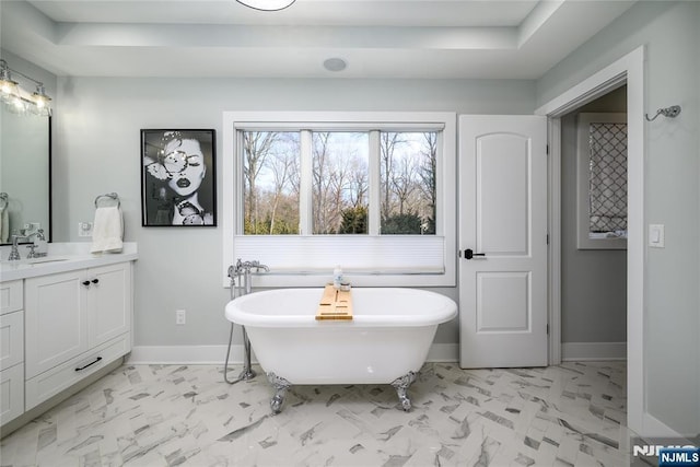 full bathroom featuring a soaking tub, baseboards, marble finish floor, and vanity