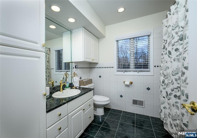 full bathroom with visible vents, toilet, tile patterned flooring, vanity, and tile walls