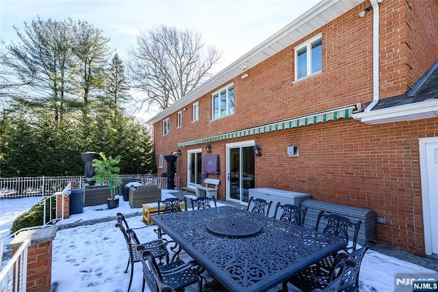 snow covered patio featuring outdoor dining area and fence