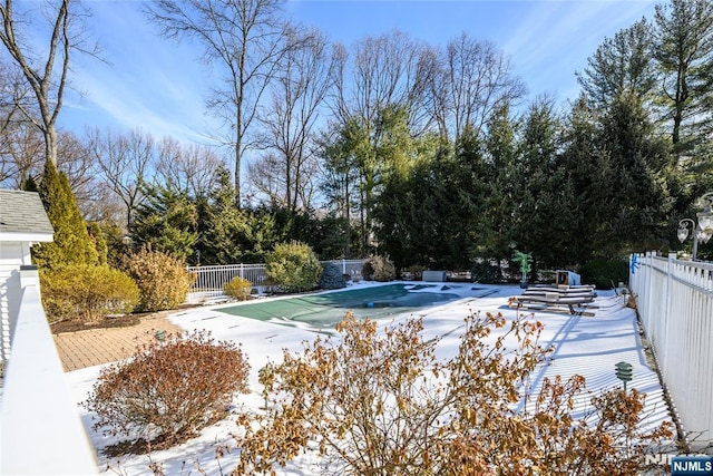 snow covered pool with a patio area, fence, and a covered pool