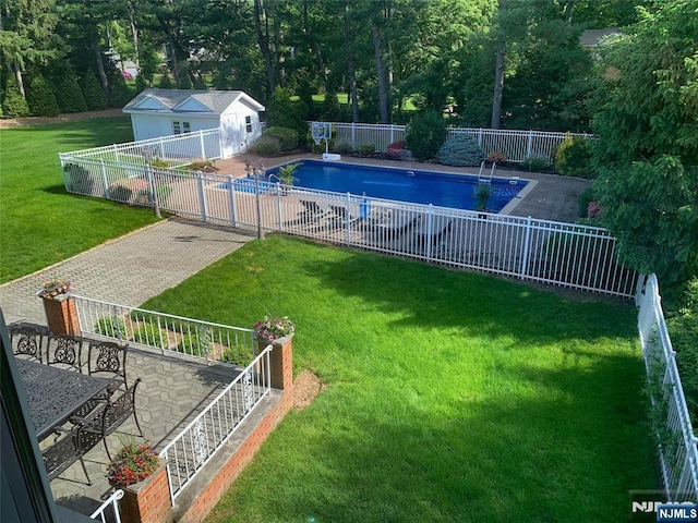 view of swimming pool with a fenced in pool, an outbuilding, a fenced backyard, and a yard