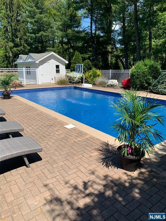 outdoor pool featuring fence, a patio, and an outbuilding