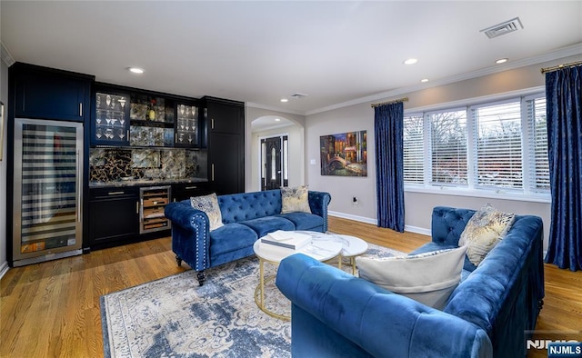 living room featuring beverage cooler, a dry bar, arched walkways, and visible vents