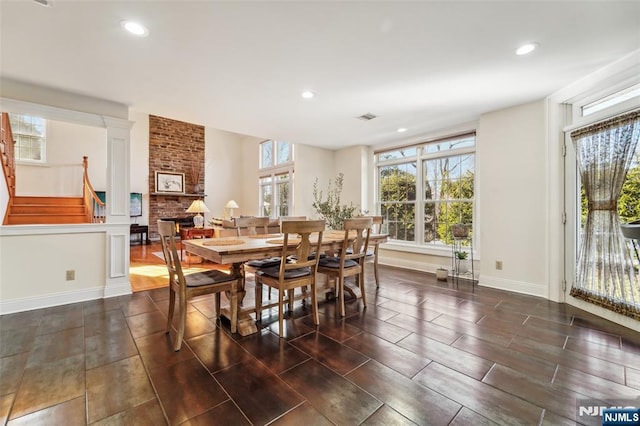 dining room featuring a healthy amount of sunlight, a brick fireplace, visible vents, and recessed lighting