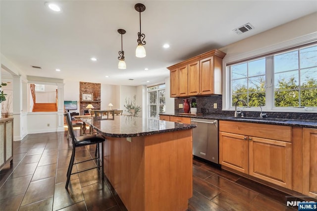 kitchen featuring a center island, tasteful backsplash, visible vents, stainless steel dishwasher, and a healthy amount of sunlight