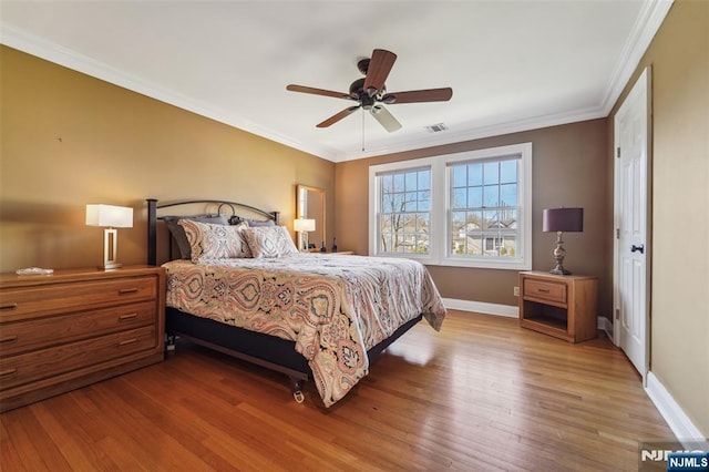 bedroom featuring baseboards, visible vents, wood finished floors, and ornamental molding