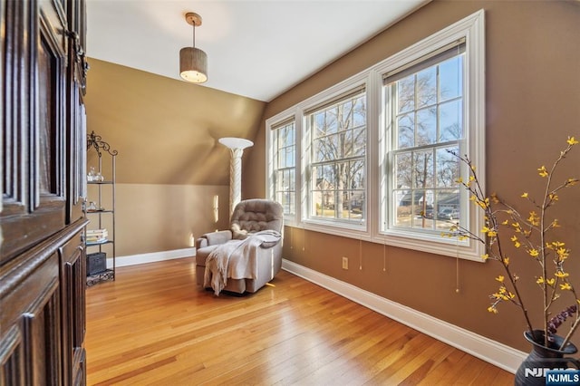 living area with lofted ceiling, light wood-style flooring, and baseboards