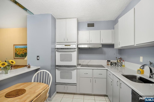 kitchen featuring double oven, white cabinetry, sink, black electric stovetop, and light tile patterned floors