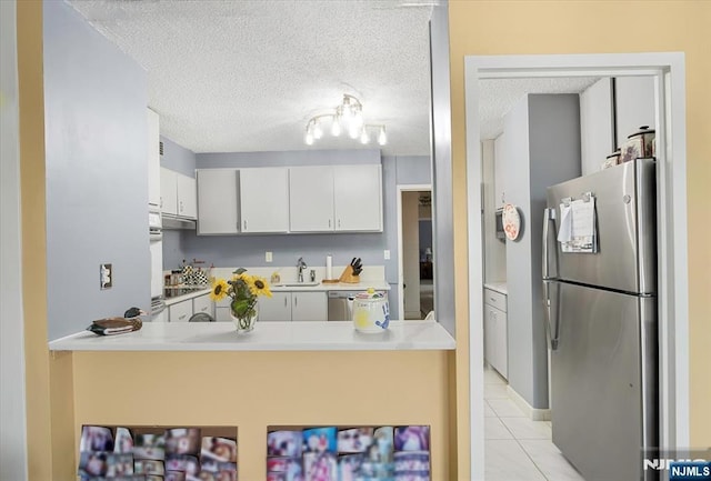 kitchen featuring appliances with stainless steel finishes, white cabinetry, sink, light tile patterned floors, and a textured ceiling