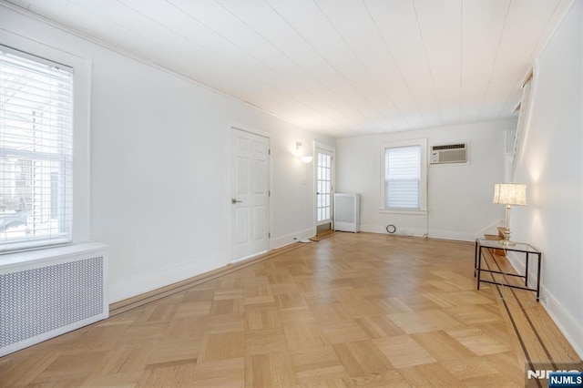 spare room with radiator, light parquet floors, and a wall mounted AC