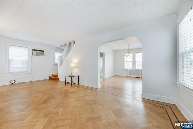 spare room with light parquet floors, radiator, and a wall unit AC