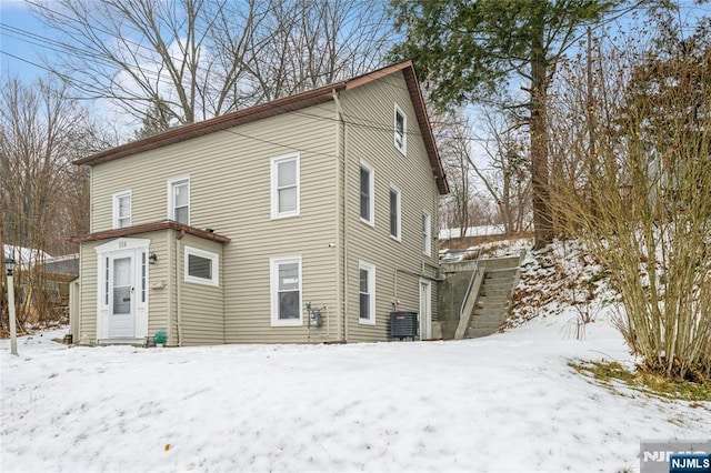 snow covered property featuring central AC unit