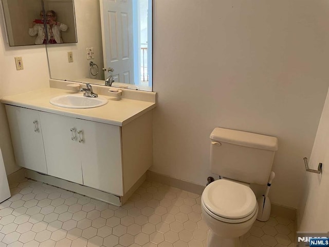 half bathroom featuring baseboards, vanity, and toilet