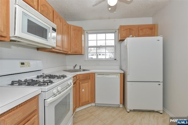 kitchen featuring a textured ceiling, ceiling fan, white appliances, a sink, and light countertops