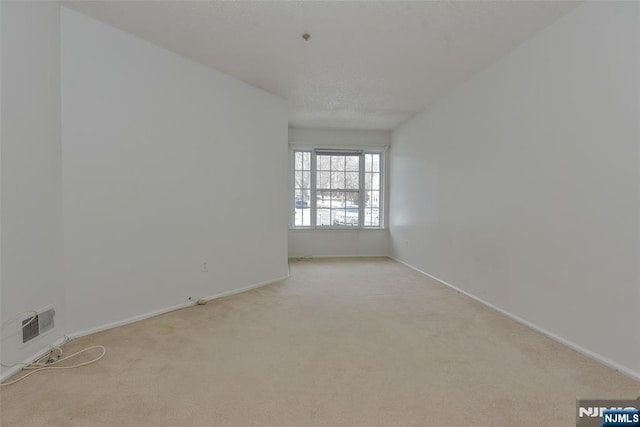 unfurnished room featuring light carpet, visible vents, and baseboards